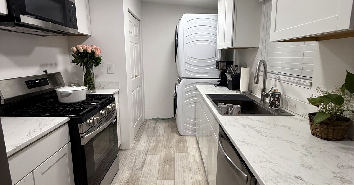 Finished compact galley kitchen with white cabinetry, stone-look counters and gray plank flooring