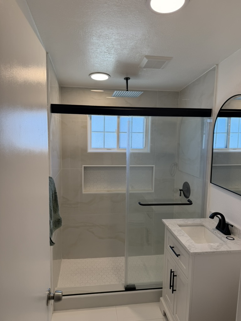 Finished Heatherdale restroom remodel with a tiled walk-in shower, glass enclosure, recessed niche and white vanity