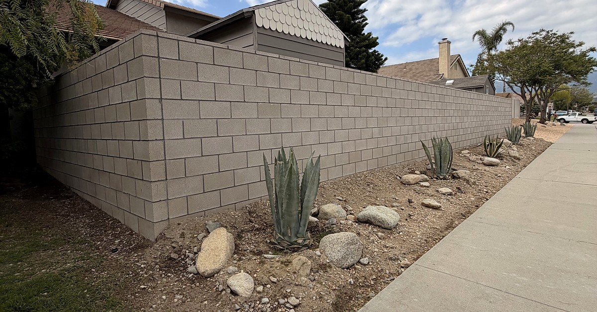 Completed gray concrete masonry block privacy wall built by K&A Builders in Rialto California